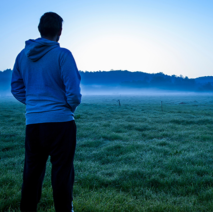 Man standing in misty field at dawn